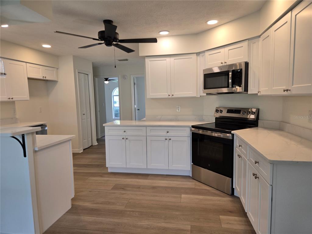 719 Balmoral Court Inverness, FL 34453 - Photo 10 of 29 a kitchen with stainless steel appliances kitchen island granite countertop a refrigerator a sink dishwasher a stove and white cabinets with wooden floor