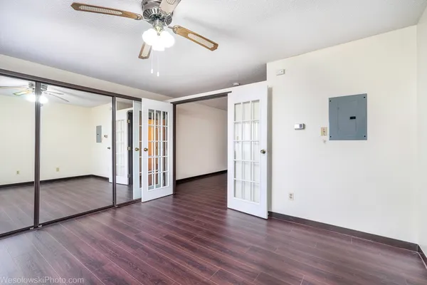 an empty room with wooden floor chandelier fan and windows