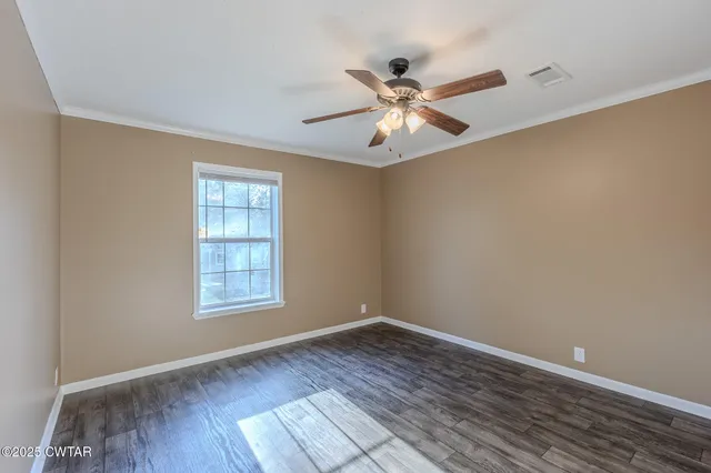 an empty room with wooden floor fan and windows