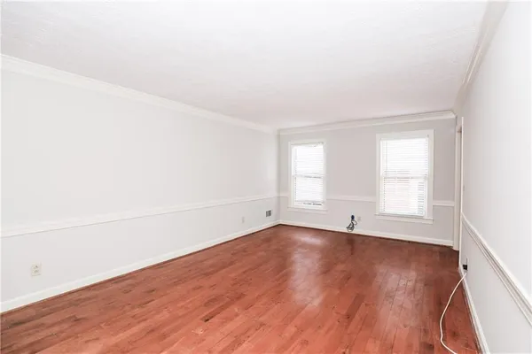an empty room with wooden floor ceiling fan and windows