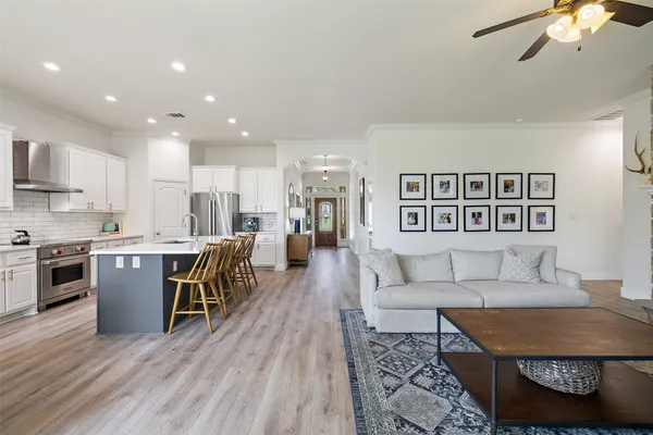 a living room with stainless steel appliances furniture and a kitchen view