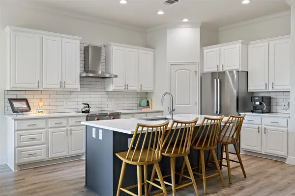 a kitchen with stainless steel appliances granite countertop a table chairs sink refrigerator and cabinets