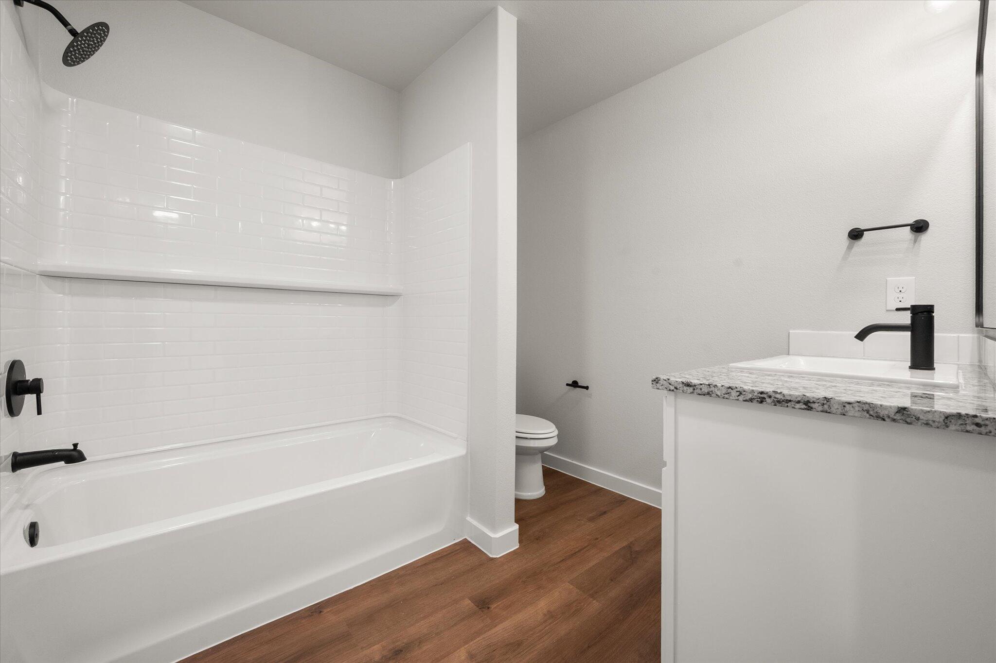 8607 29th Street Lubbock, TX 79407 - Photo 14 of 20 a bathroom with a granite countertop sink toilet and bathtub