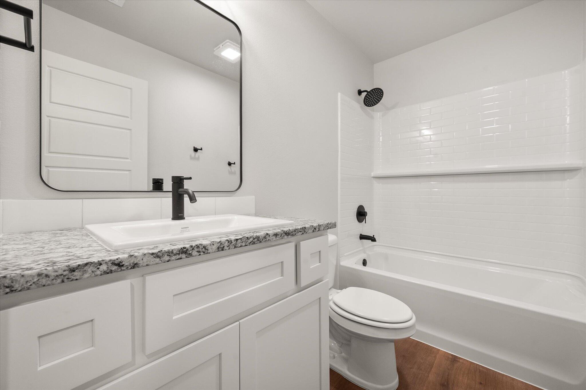 8607 29th Street Lubbock, TX 79407 - Photo 17 of 20 a bathroom with a granite countertop toilet sink and mirror