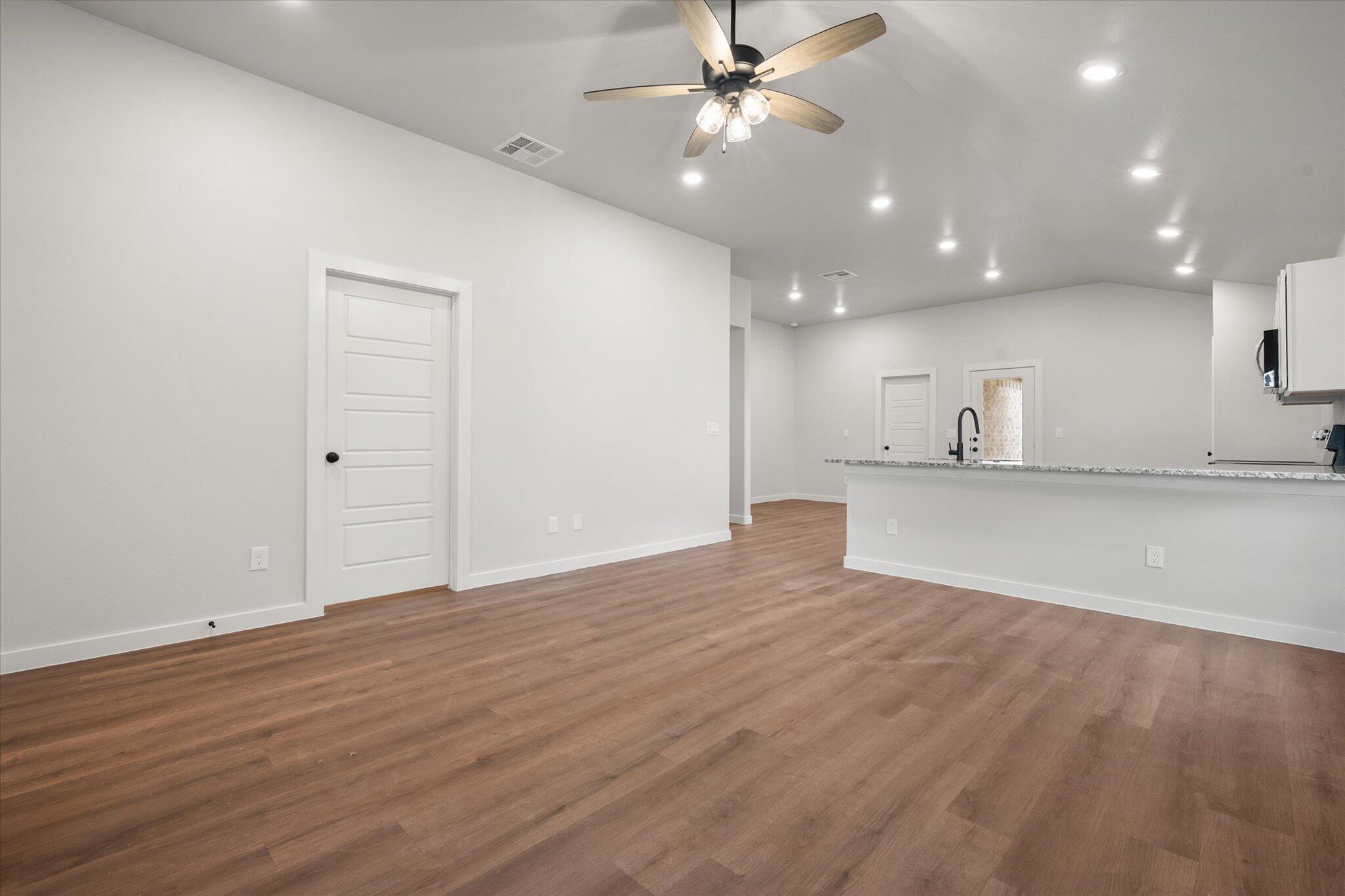 8607 29th Street Lubbock, TX 79407 - Photo 3 of 20 a view of an empty room with wooden floor and a ceiling fan