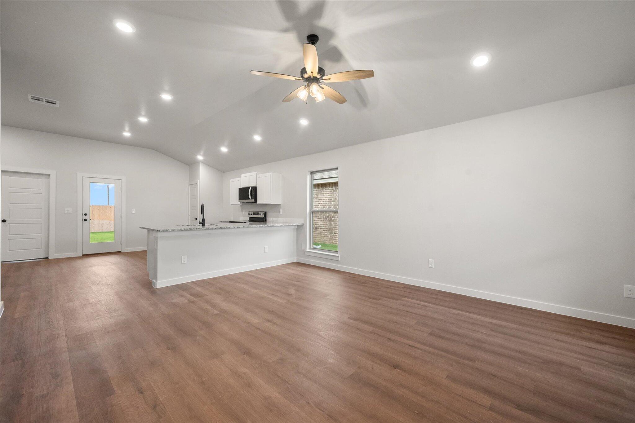 8607 29th Street Lubbock, TX 79407 - Photo 4 of 20 a view of an empty room and kitchen with wooden floor