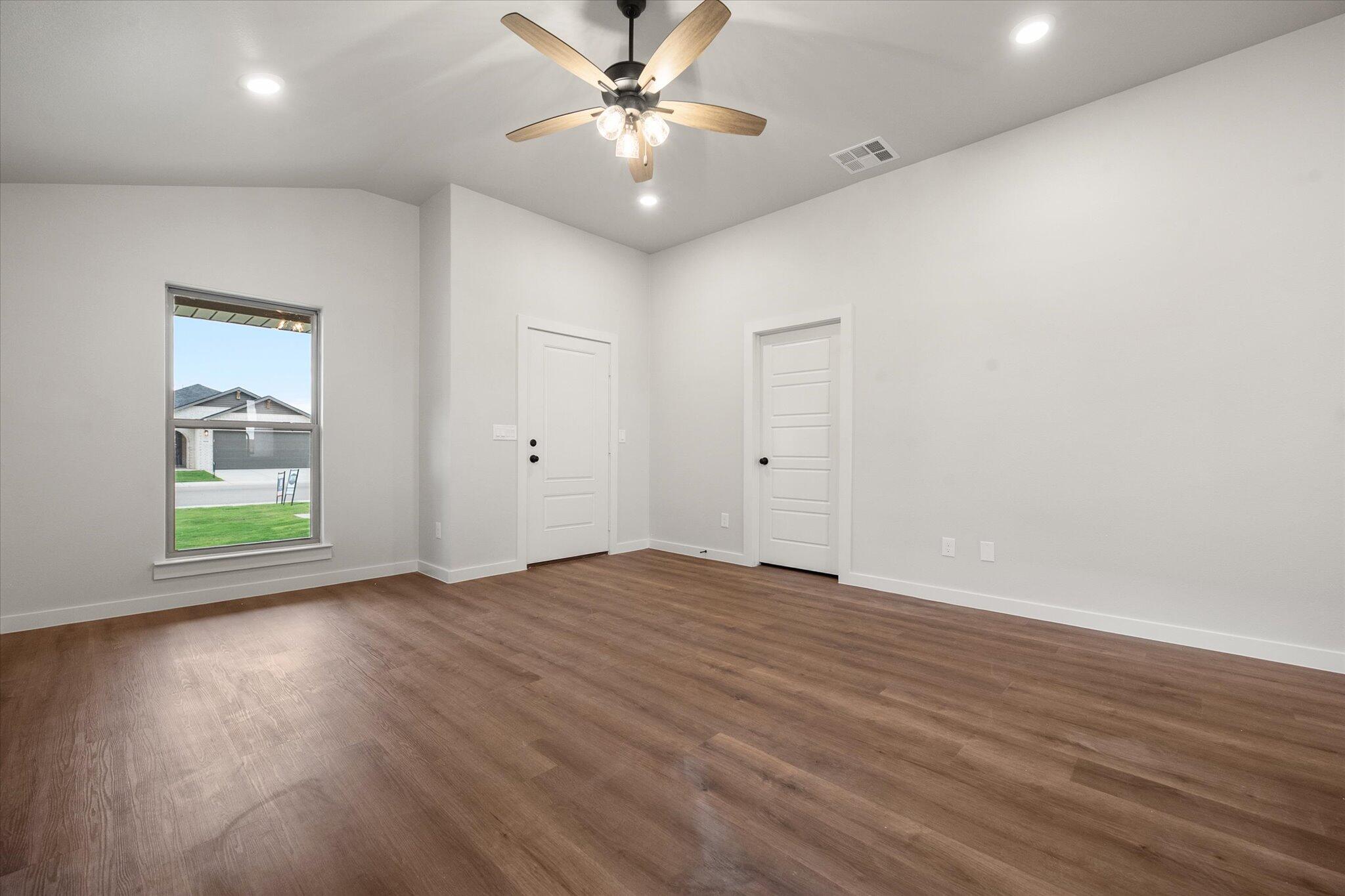 8607 29th Street Lubbock, TX 79407 - Photo 5 of 20 an empty room with wooden floor chandelier fan and windows