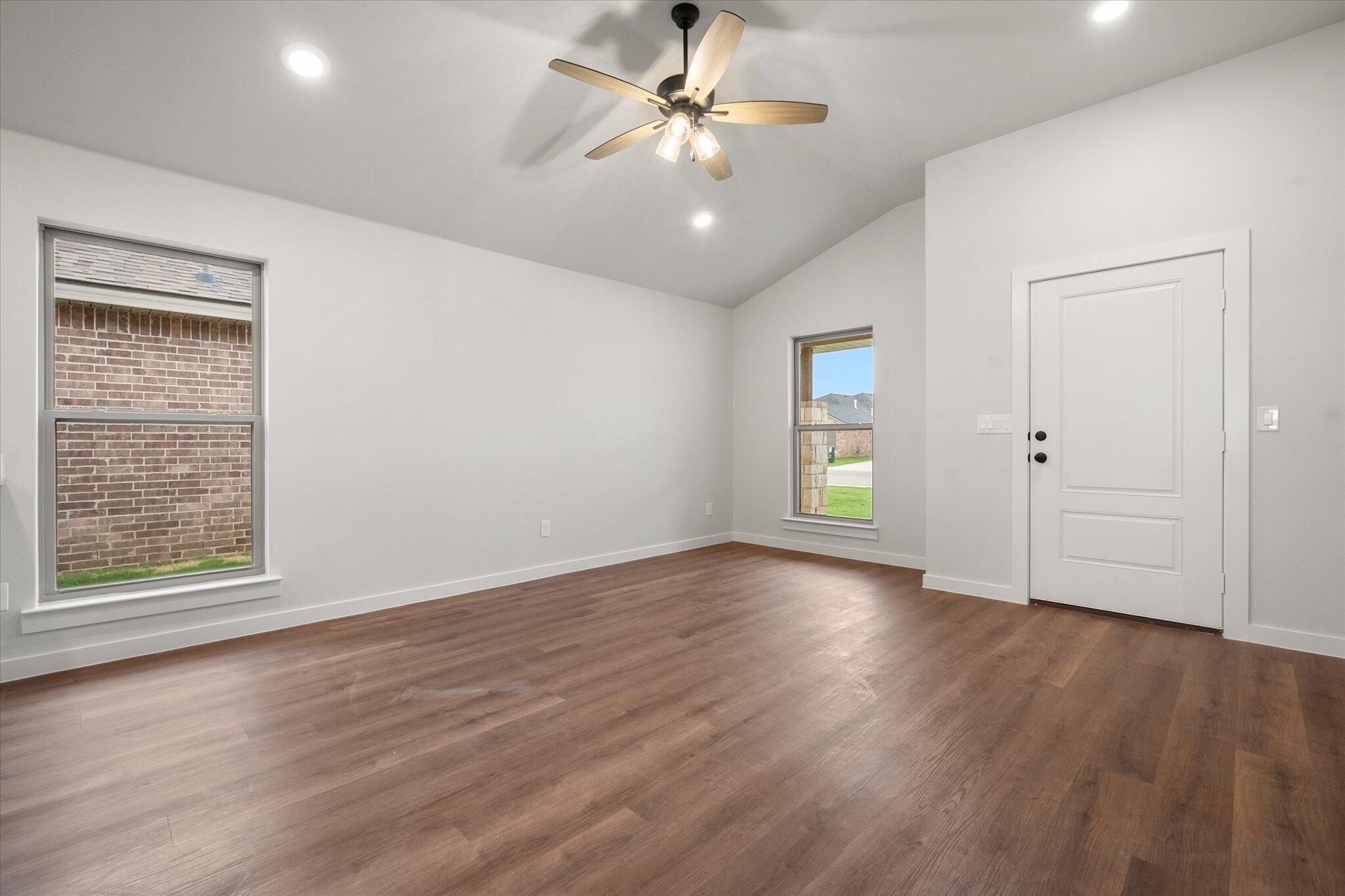 8607 29th Street Lubbock, TX 79407 - Photo 6 of 20 an empty room with wooden floor chandelier fan and windows