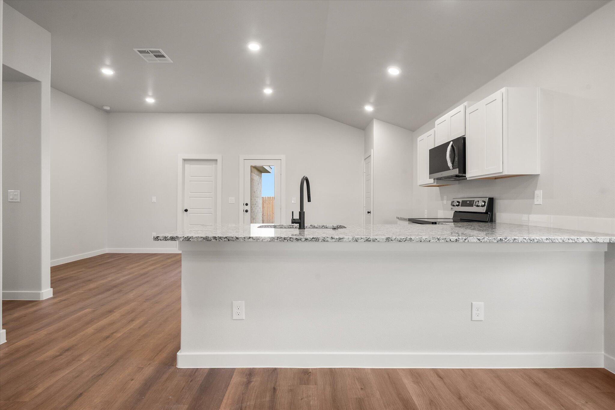 8607 29th Street Lubbock, TX 79407 - Photo 7 of 20 a kitchen with stainless steel appliances granite countertop a sink a stove and a refrigerator
