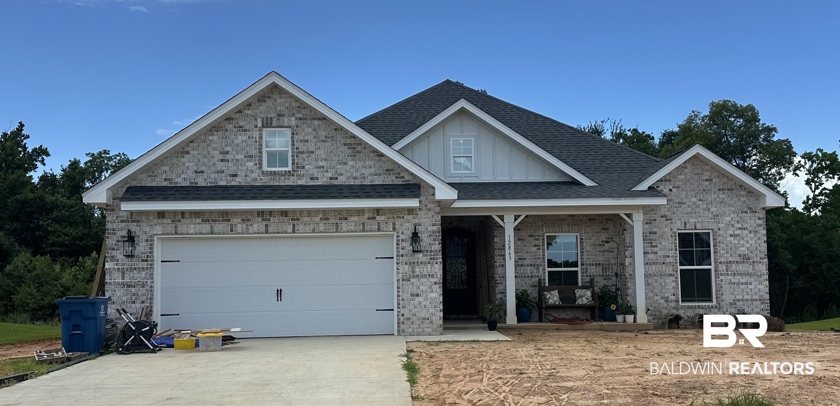 12863 Flanagan Street Elberta, AL 36530 - Photo 1 of 14 View of front of house featuring concrete driveway, brick siding, board and batten siding, a garage, and a porch