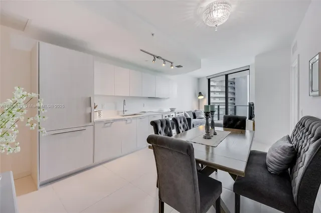 a kitchen with stainless steel appliances granite countertop a dining table chairs refrigerator and cabinets