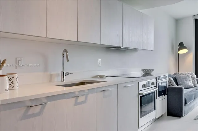 a kitchen with stainless steel appliances granite countertop white cabinets and a sink