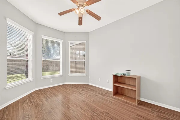 a view of an empty room with a window and wooden floor