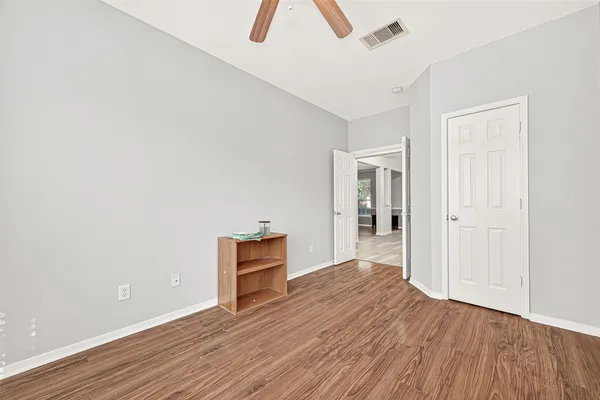 an empty room with wooden floor and a ceiling fan