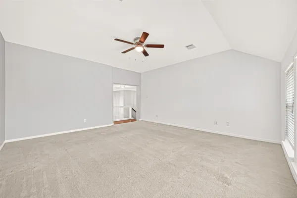 an empty room with windows and fan