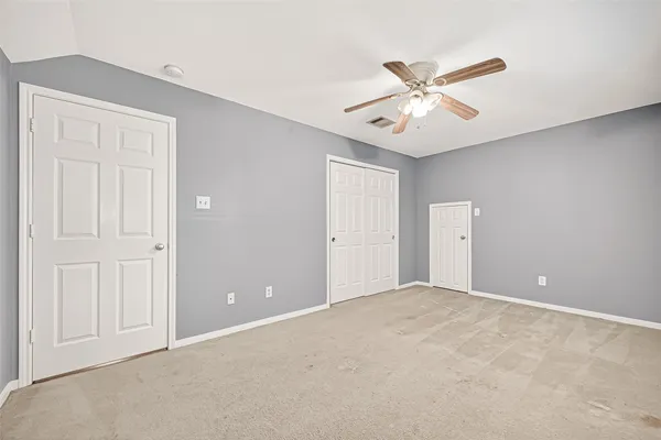 a view of an empty room and chandelier fan