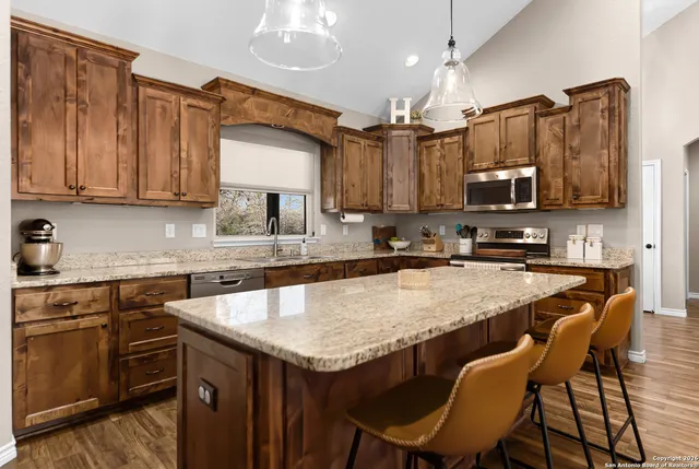 a kitchen with granite countertop a table chairs microwave and refrigerator