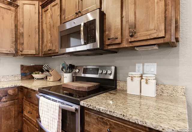 a kitchen with granite countertop stainless steel appliances a sink and cabinets