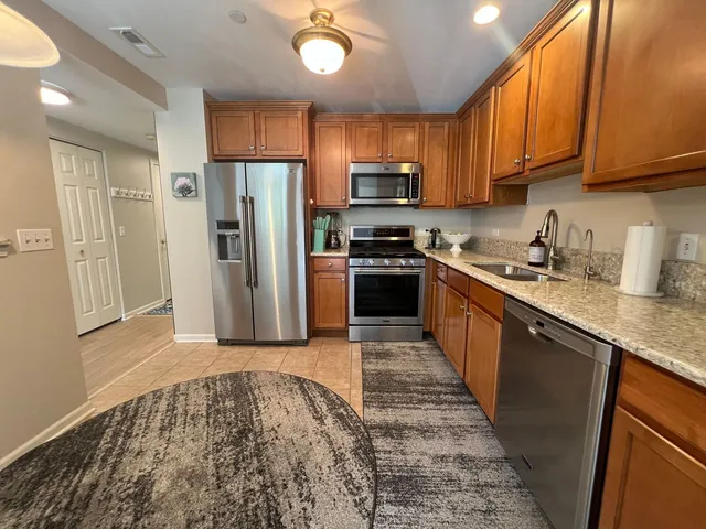 a kitchen with stainless steel appliances granite countertop a refrigerator stove top oven a sink and dishwasher with wooden floor