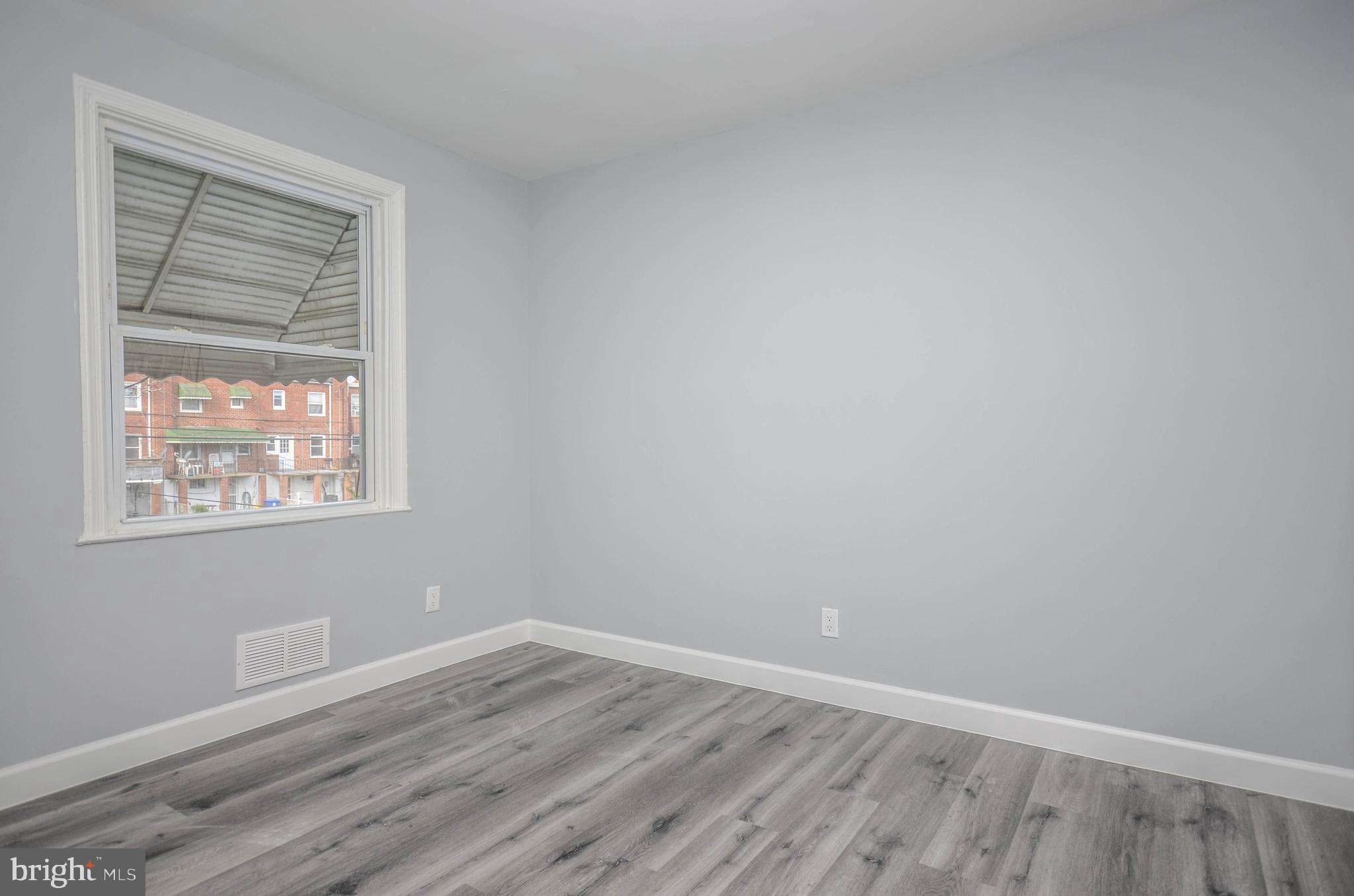 3917 Dudley Avenue Baltimore, MD 21213 - Photo 13 of 23 an empty room with wooden floor and windows