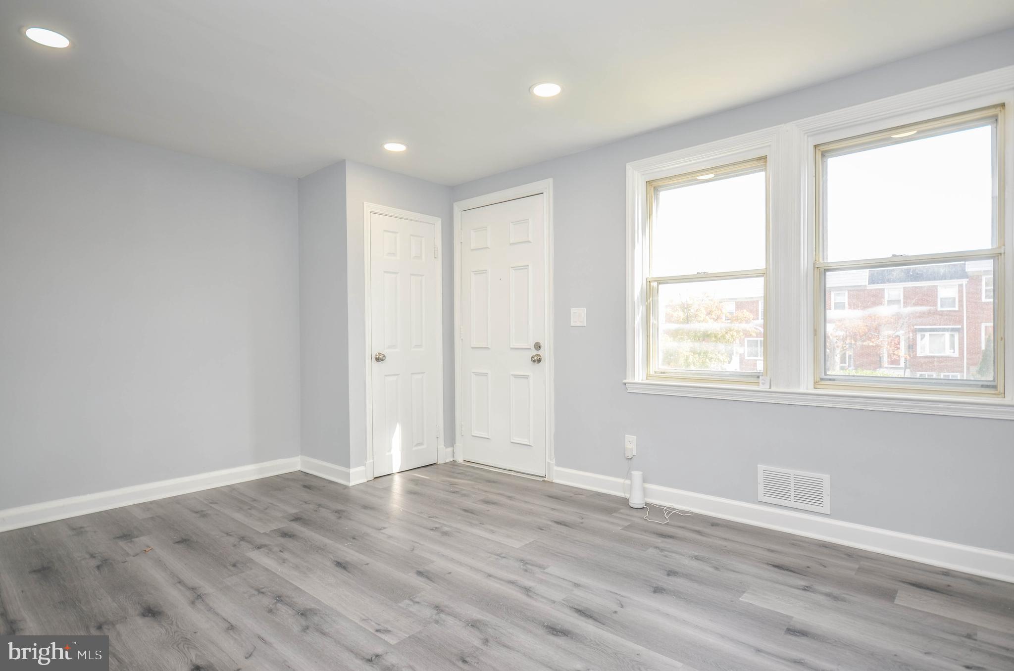 3917 Dudley Avenue Baltimore, MD 21213 - Photo 4 of 23 an empty room with wooden floor and windows