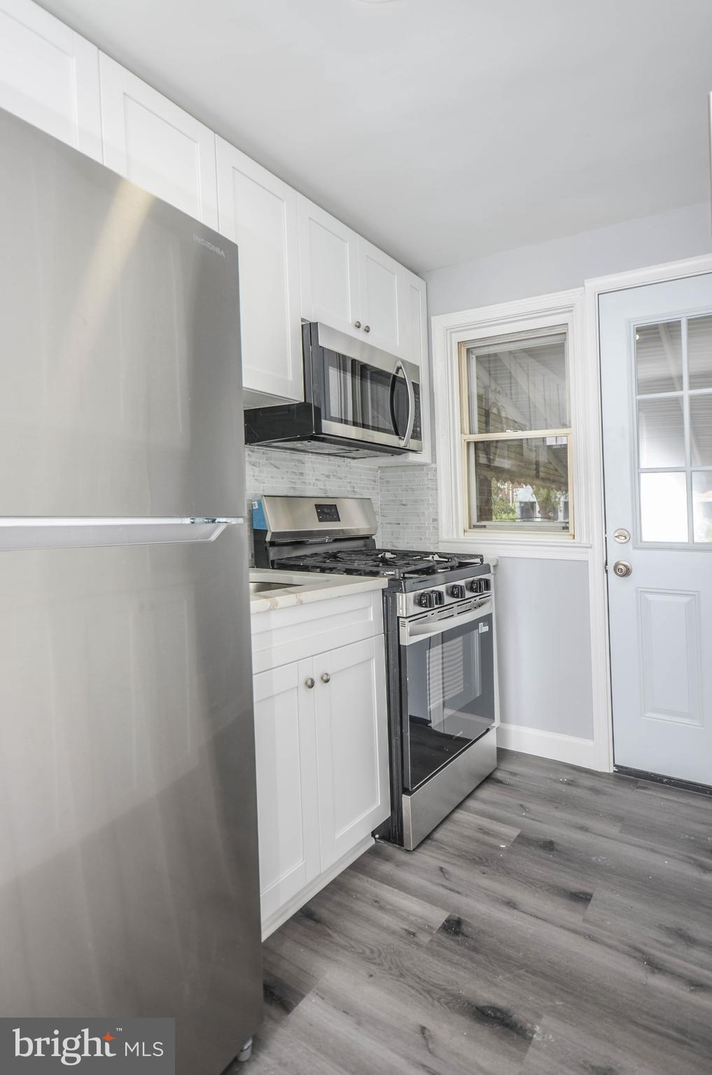 3917 Dudley Avenue Baltimore, MD 21213 - Photo 8 of 23 a kitchen with stainless steel appliances a refrigerator stove and microwave
