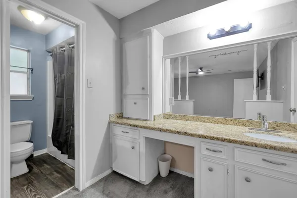a en suite bathroom with a granite countertop sink and a mirror