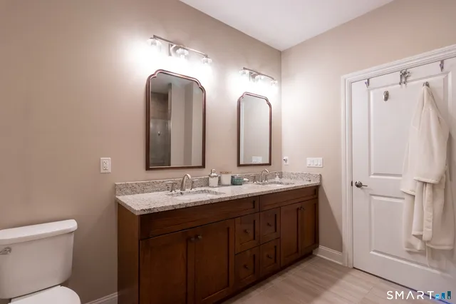 a bathroom with a double vanity sink and mirror with toilet