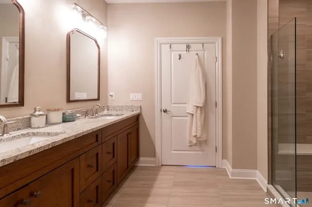 a spacious bathroom with a double vanity sink a mirror and a shower