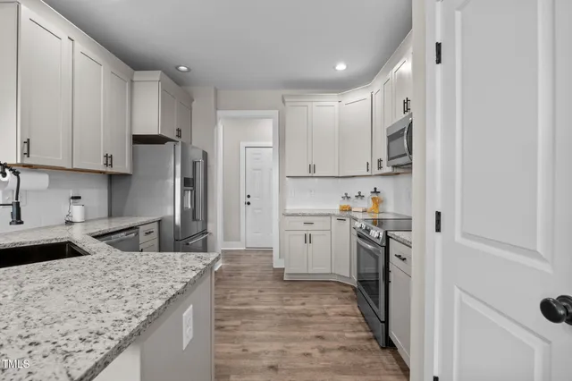 a kitchen with a sink white cabinets and appliances
