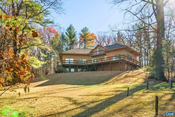 a backyard of a house with large trees and outdoor seating