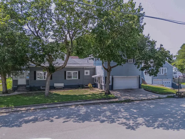 a front view of a house with a yard and large tree