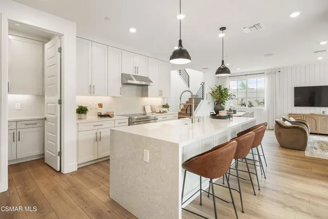 a kitchen with stainless steel appliances kitchen island wooden floors and white cabinets