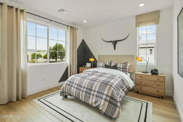 a bedroom with a bed a window and potted plant on the dresser