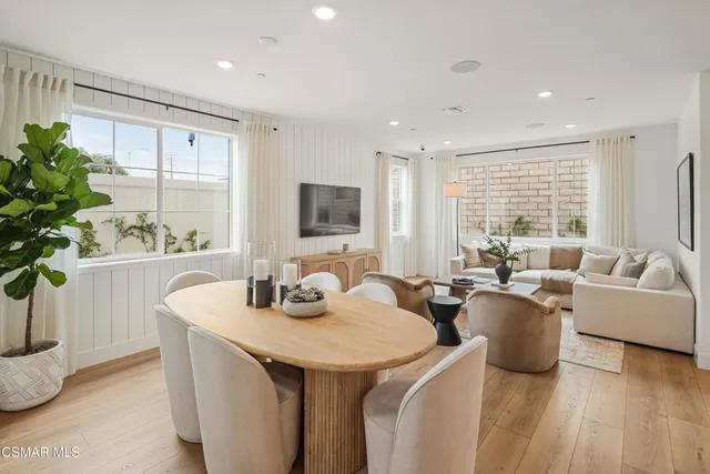 a dining room with furniture a potted plant and a large window