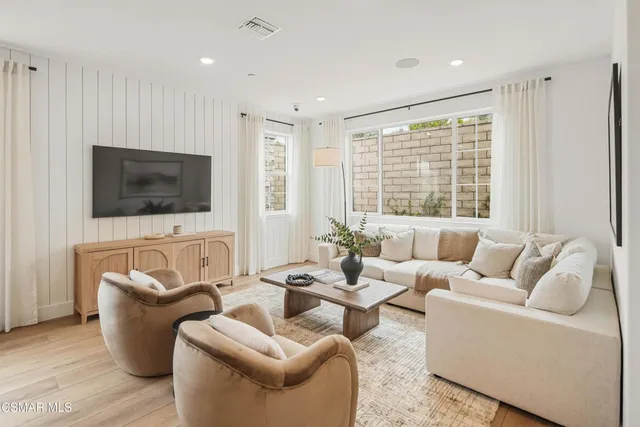 a living room with furniture a flat screen tv and a large window