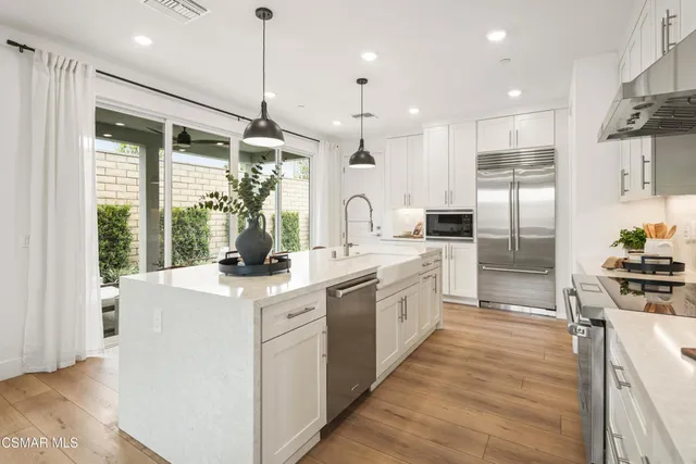 a kitchen with stainless steel appliances granite countertop a sink a stove and a refrigerator