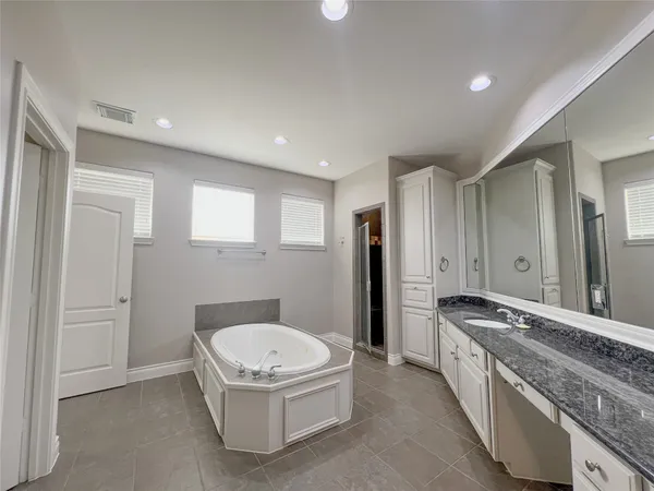 a spacious bathroom with a granite countertop tub sink and mirror