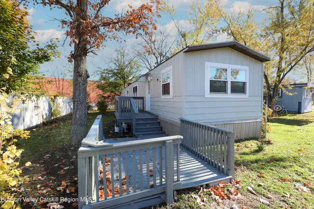 a view of a house with wooden deck and a small yard