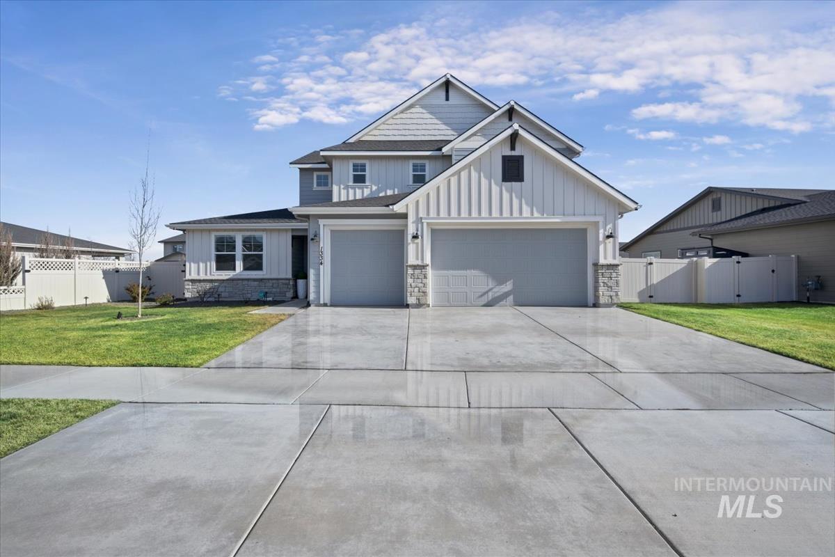 View of front of property featuring board and batten siding, a gate, stone siding, and concrete driveway
