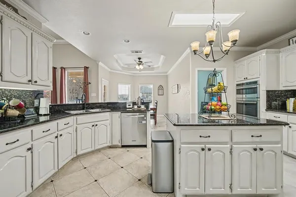 a kitchen with white cabinets and chandelier
