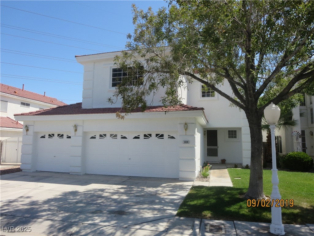 View of front of property featuring concrete driveway, stucco siding, an attached garage, a front yard, and a tile roof