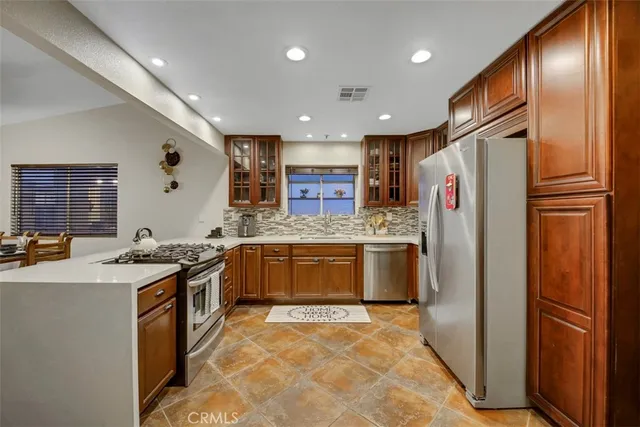 a kitchen with stainless steel appliances granite countertop a refrigerator a stove and a sink