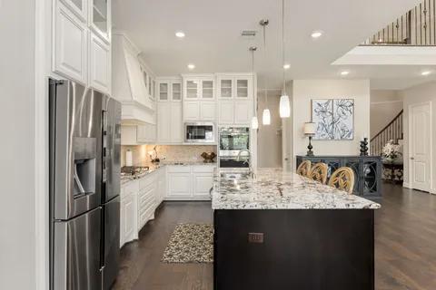 a large kitchen with stainless steel appliances kitchen island granite countertop a refrigerator and a sink