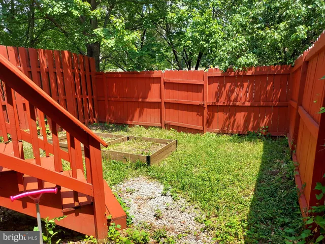 a view of a yard with plants and wooden fence