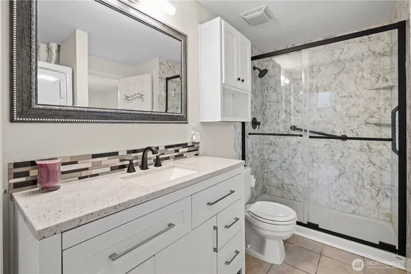 a bathroom with a granite countertop sink mirror vanity and toilet