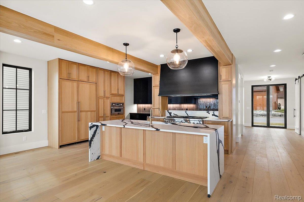 13459 Haddon Street Fenton, MI 48430 - Photo 11 of 84 Kitchen with light wood finish cabinetry, beam ceiling, light wood finished floors, ventilation hood, and a spacious island