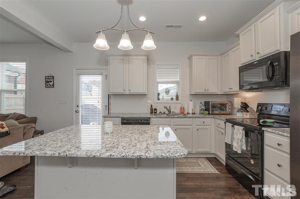 42 Griffith Place Clayton, NC 27520 - Photo 7 of 26 a kitchen with kitchen island granite countertop stainless steel appliances a sink a stove cabinets counter space and a window