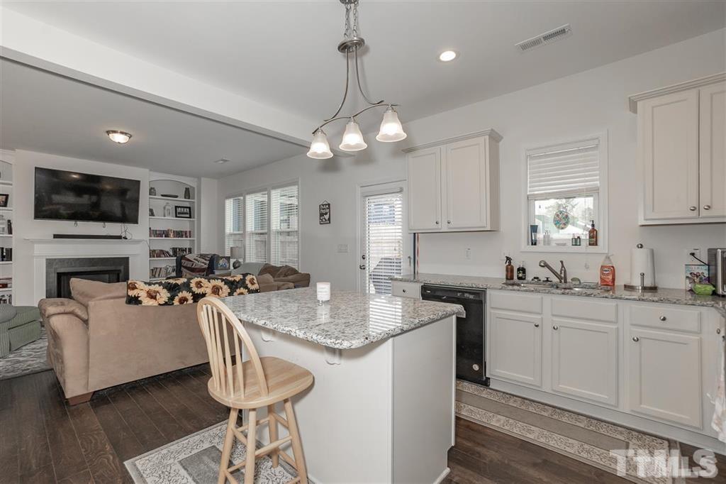 42 Griffith Place Clayton, NC 27520 - Photo 8 of 26 a kitchen with granite countertop a stove a sink dishwasher a dining table and chairs with wooden floor