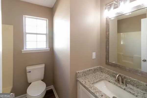a bathroom with a granite countertop toilet a sink and mirror